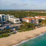 A woman sits at a cafe table with a map, laptop showing overwater bungalows, and a passport, thoughtfully planning her next tropical vacation to one of the Playa Largo Resort . The backdrop is a sunlit beach seen through large windows.