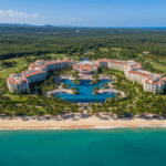 Aerial view of the Hyatt Regency Grand Reserve Puerto Rico resort, showing the expansive hotel complex, lush surrounding golf courses and jungle, a massive lagoon-style pool, and a pristine beach with turquoise ocean water.