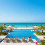 Modern, luxury infinity pool and resort buildings at Atelier Playa Mujeres Resort, with beach and turquoise ocean in the background.