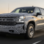 A side profile view of the 2027 Chevy Silverado 1500 High Country featuring flatter wheel arches and a sleek, redesigned front fascia. The truck is finished in a metallic Iridescent Pearl, highlighting its more modern and purposeful body proportions.