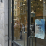 The glass storefront of an Eddie Bauer retail location features a prominent blue and white "Bankruptcy Filing" notice taped to the front door.