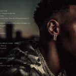 A young man with short, dark hair, wearing a patterned hoodie and a thick chain, gazes thoughtfully into the distance, with a digital tracklist behind him. His contemplative expression suggests reflection on his music and life, set against the backdrop of his discography.