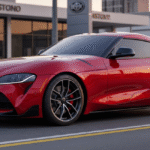 A vibrant red Toyota Supra is parked on a street in front of a modern Toyota dealership, showcasing its sleek design. The car's dynamic lines and aggressive styling are prominently featured against the dealership's contemporary architecture.