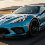 Blue Chevrolet Corvette C8 Corvette Grand Sport speeding on a racetrack at sunset, front three-quarter angle with black wheels.