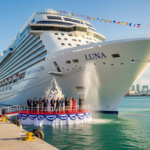 Norwegian Luna is christened in Miami as a bottle breaks on the bow before a cheering crowd; Norwegian Cruise Line branding is visible on the hull.