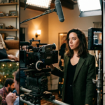 A collage showing various moments, including a woman laughing on a leather sofa and standing behind a professional film camera. The Aubrey Plaza collection captures the balance between a busy filming schedule and private family time.