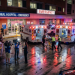 Ambulances and police vehicles crowd the emergency entrance of Memorial Regional Hospital under red and blue lights.