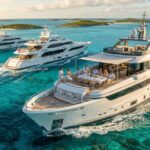Three superyachts from Bahamas Luxury Yacht Charters cruise turquoise waters with guests dining on the aft deck.