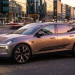 Copper 2027 Polestar 4 Luxury coupe-SUV parked on a European city street at golden hour. Sleek body lines and Thor’s Hammer headlights reflect sunset as pedestrians walk by.